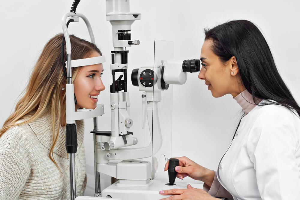 optometry_The doctor checks the patient's throat. Consultant in the ophthalmology office. Apparatus for checking vision on a white wall background.