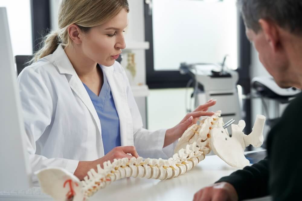 chiropractor_Caucasian female doctor talking with patient about his spine