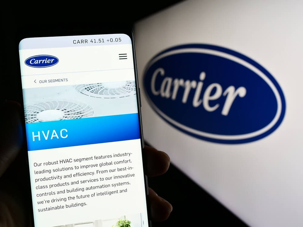 HVAC website_Stuttgart, Germany - 04-28-2023: Person holding mobile phone with webpage of US company Carrier Global Corporation on screen in front of logo. Focus on center of phone display. Unmodified photo