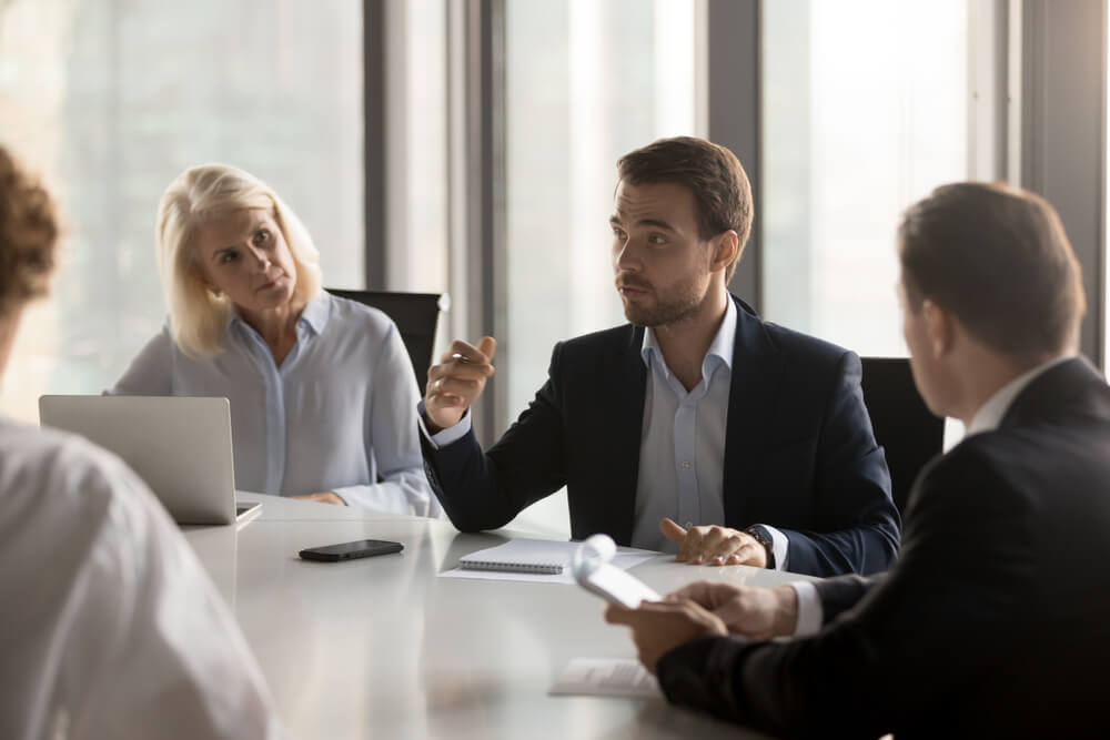 marketing director_Serious diverse colleagues brainstorm at conference table discuss project at meeting, focused businesspeople talk negotiating in office at briefing, business partners speak considering cooperation