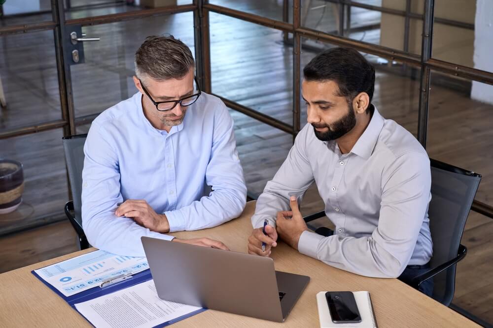 marketing service_Diverse business people businessmen planning working together at boardroom meeting using laptop pc computer. Multiethnic executive team discussing financial report sitting at table in office.