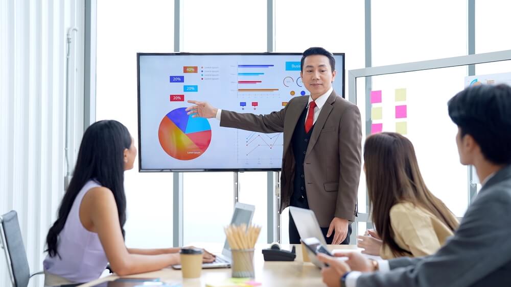 CMO_Professional marketing manager presenting pie chart of business strategy planing communicating with marketing officer team in meeting hour in conference room business working concept