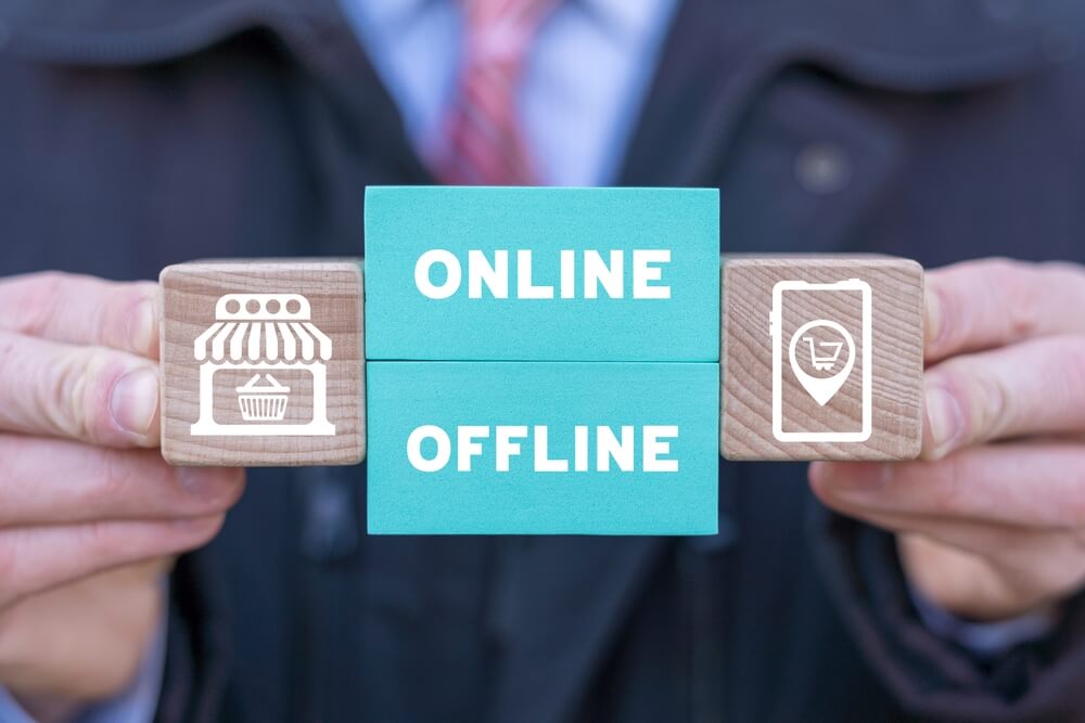 online offline marketing_Man holding colorful blocks with icons and inscription: ONLINE OFFLINE. Transition from online to offline or vice versa in commerce, business, retail. Choose between online and offline.