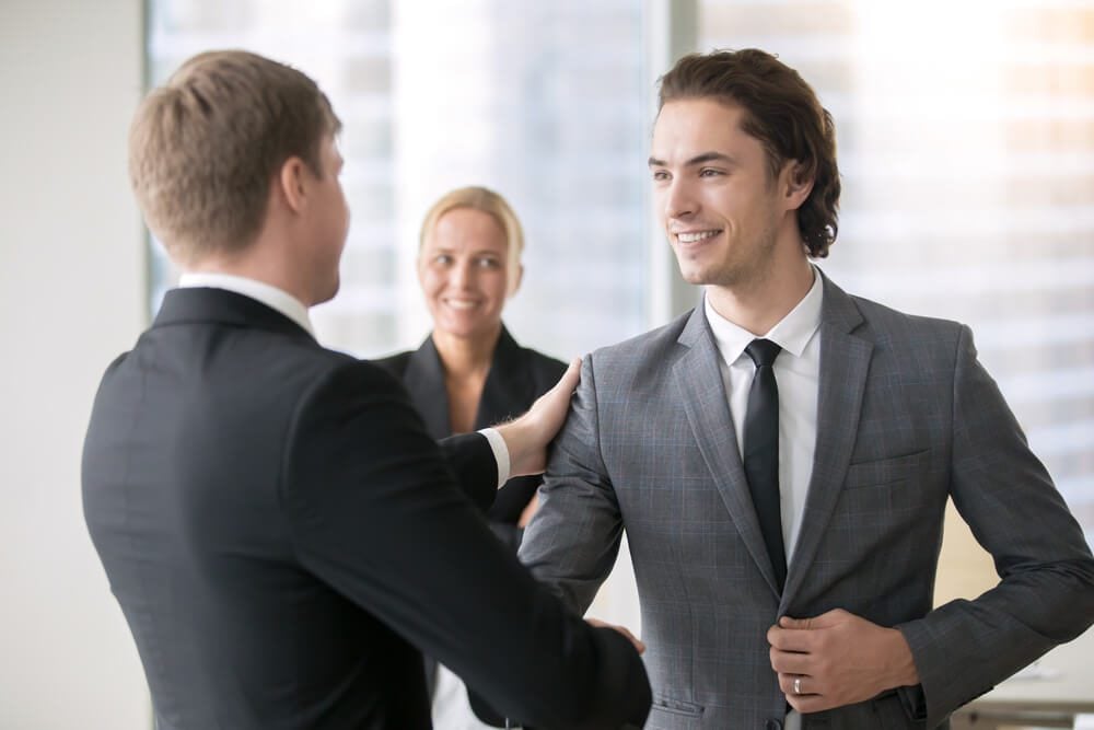 hire CMO_Boss promoting male subordinate. Two businessmen handshaking, congratulating on promotion, hired young consultant, promising innovation, ready for new heights, getting higher pay rate, financial bonus