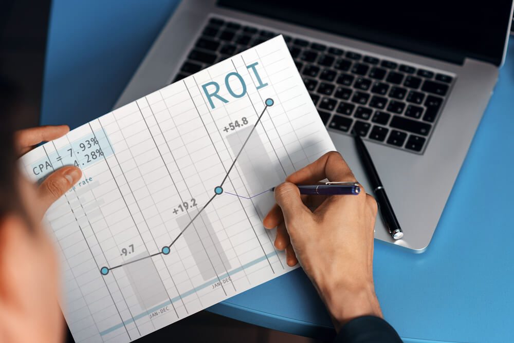 analytics ROI_Manager makes a note on the graph of conversion sales and return on investment ROI. Internet marketing with the schedule up. Good indicators of contextual advertising.