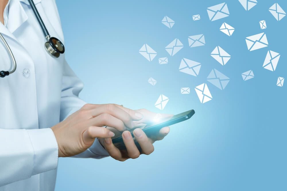 healthcare email_Doctor works with letters in envelopes on blue background.