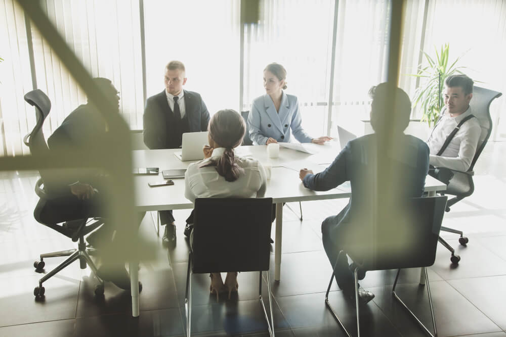 organizational_Silhouettes of people sitting at the table. A team of young businessmen working and communicating together in an office. Corporate businessteam and manager in a meeting