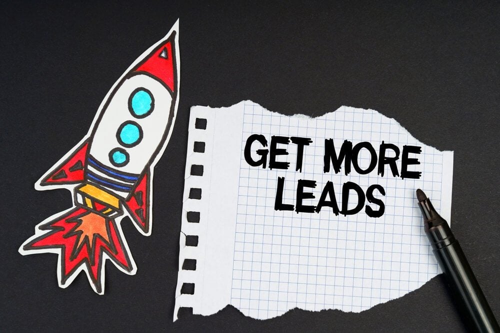 lead generation_Business and finance concept. On a black background, a rocket, a marker and paper with the inscription - GET MORE LEADS