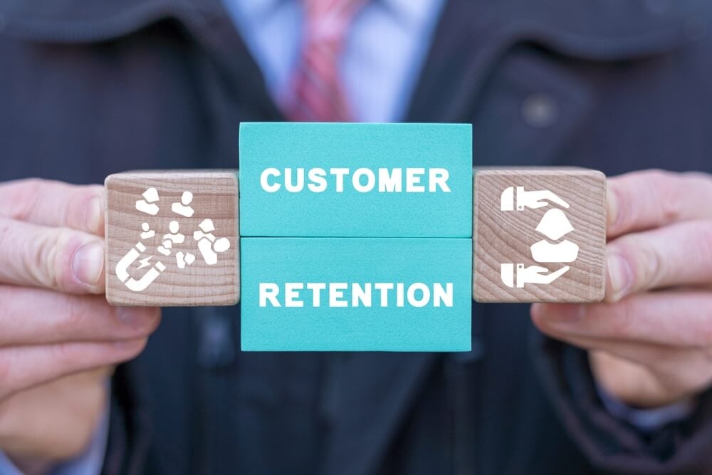 customer retention_Man holding colorful blocks with icons and inscription: CUSTOMER RETENTION. Concept of customer acquisition and retention business marketing. Incentive and welfare program. Retain clients.