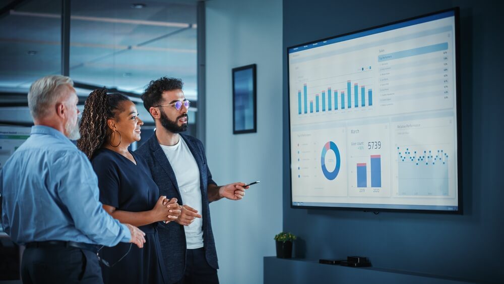 marketing analytics_Company Operations Manager Holds Meeting Presentation. Diverse Team Uses TV Screen with Growth Analysis, Charts, Statistics and Data. People Work in Business Office.