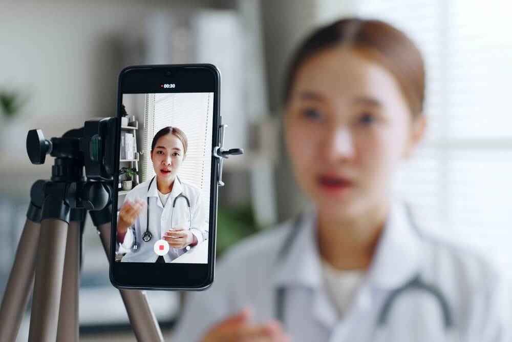 healthcare content_Asian woman doctor making online live streaming broadcast talking over camera recording in hospital, medical and healthcare blogger, vlogger concept