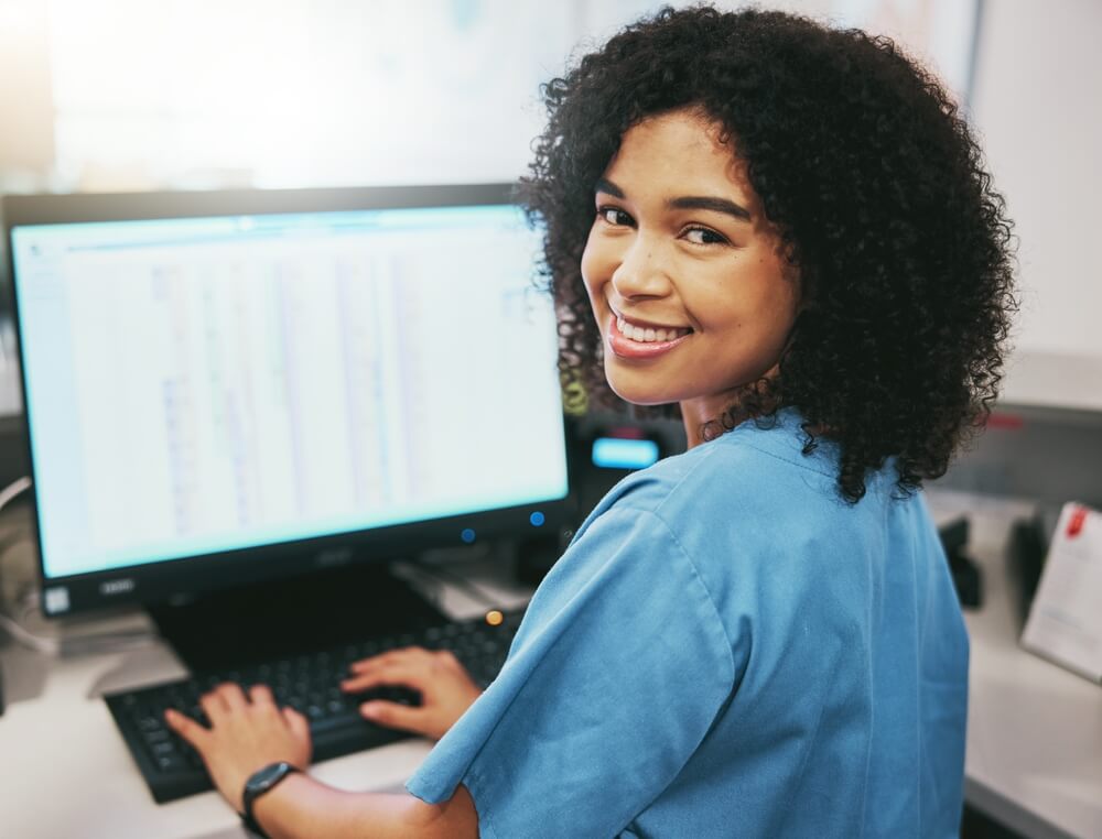 healthcare email_Portrait, nurse and receptionist at hospital on a computer working at her desk or table in an office as a black woman. Medical, healthcare professional or worker smile, happy and excited at work
