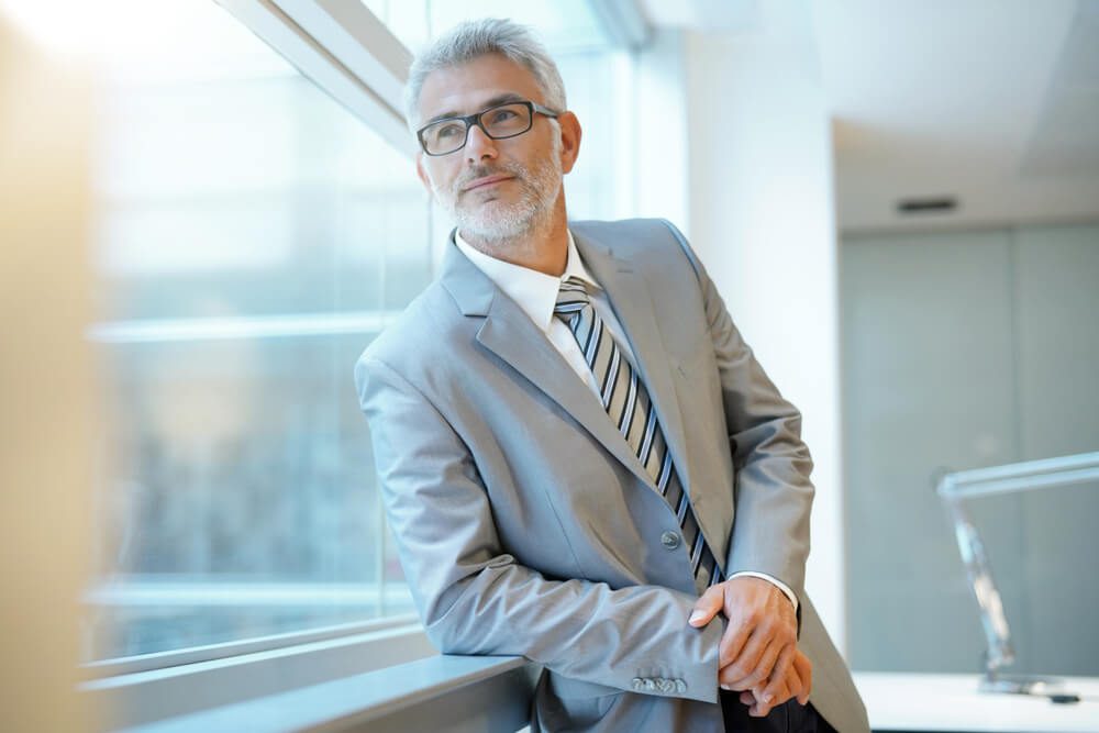 fractional CMO_Mature businessman looking out window in modern office