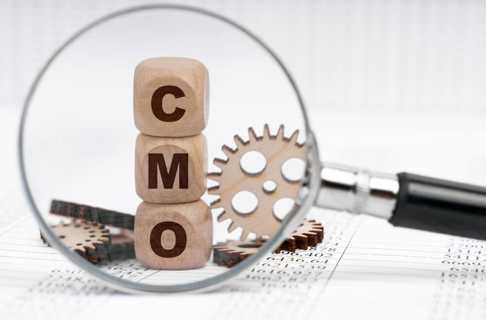 CMO_Business concept. There is a magnifying glass on the documents that points to the cubes with the inscription - CMO