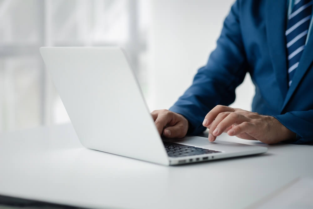 technical SEO_Person typing on laptop keyboard, businessman working on laptop, he is typing messages to colleagues and making financial information sheet to sum up the meeting.