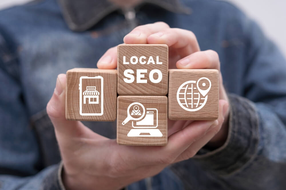 local seo_Man holding wooden cubes with icons and inscription: LOCAL SEO. Local search marketing e-commerce. Concept of local seo strategy, local search optimization.
