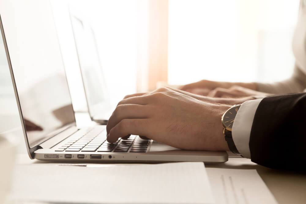 enterprise SEO_Side view of male hands typing on laptop keyboard in workplace, businessman wearing suit and luxury wristwatch working with pc computer at home office, enterprise software for business, close up