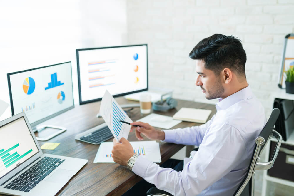 diagnostic analytics_Handsome Latin businessman examining sales data while working at home