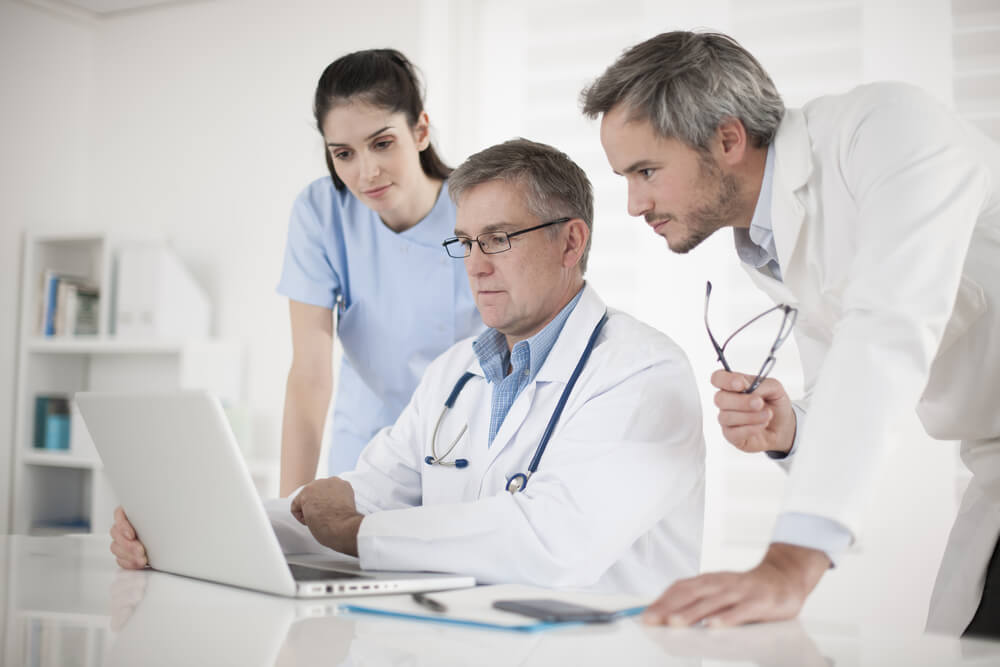 healthcare_medical team discussing around a computer