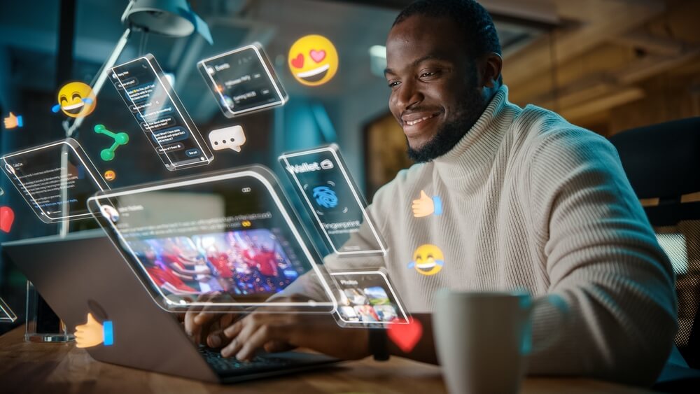 social media_African American Project Manager Working on Computer in Office. Augmented Reality Social Media Icons Appear From Worker's Laptop. Internet of Things, Internet Connectivity and Online Concept.