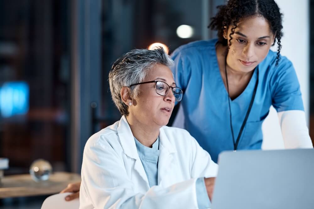 hospital ppc_Doctors, nurse or laptop in night teamwork, medical research or surgery planning in wellness hospital. Talking, thinking or healthcare women on technology for collaboration help or life insurance app