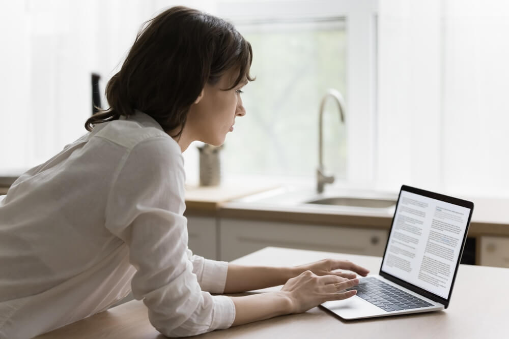 eBooks_Focused young woman typing on laptop, reading text on screen, monitor. Serious female student, author, blogger creating, editing online article, working on research study