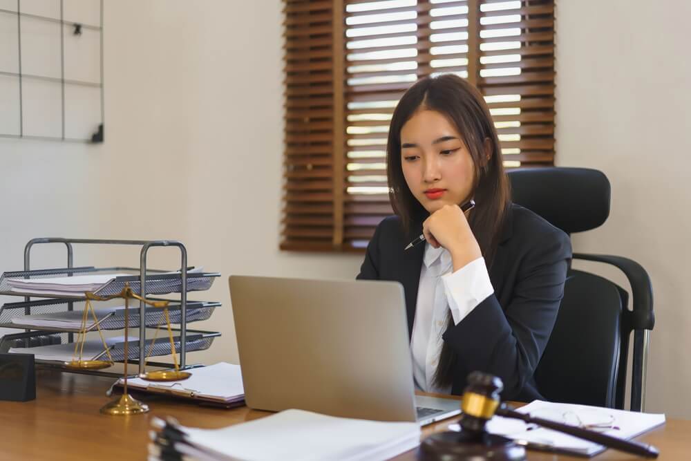 law firms_Legal and justice concept, Young female lawyer reading contract on laptop and working in law office.