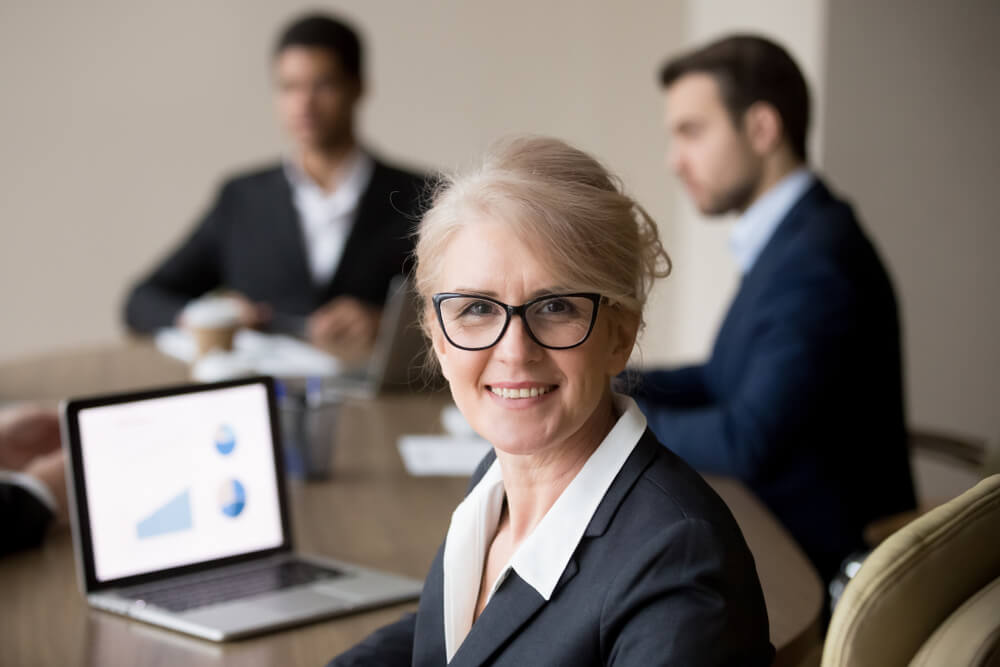 CMO_Smiling mature female company executive, professional manager, company ceo looking at camera, happy middle aged businesswoman in glasses posing at team office meeting, woman boss head shot portrait