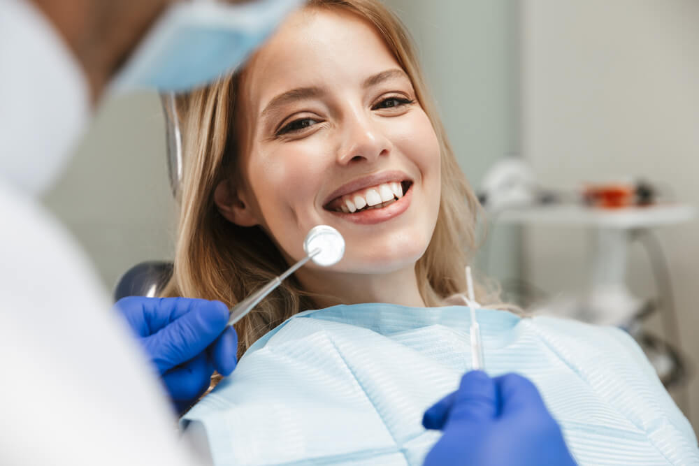 dentist_Image of satisfied young woman sitting in dental chair at medical center while professional doctor fixing her teeth