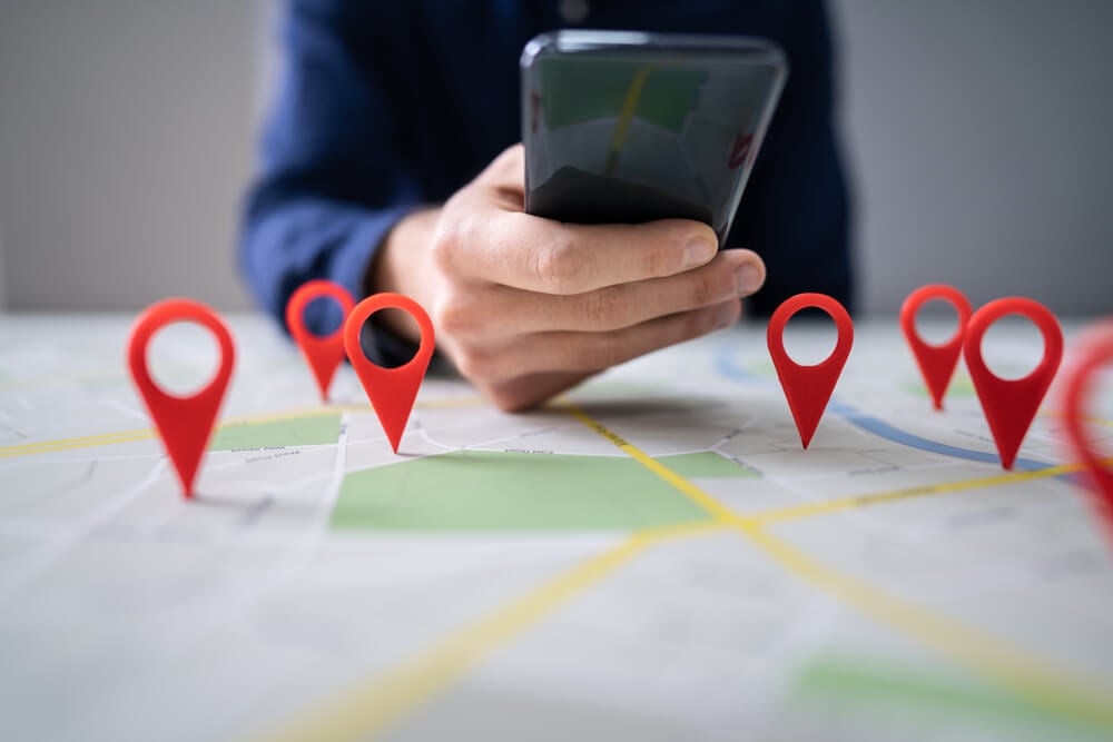 local SEO_Person Using Map With Red Location Markers On Mobile Phone