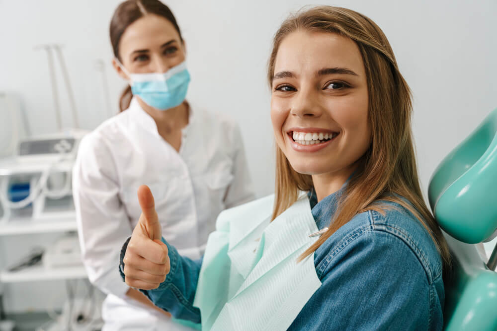 dentist patient_European young woman showing thumb up while sitting in medical chair at dental clinic