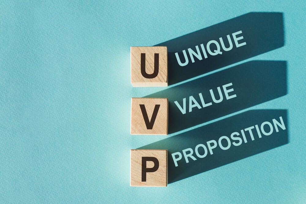 UVP_Wooden cubes building word UVP - (abbreviation Unique Value Proposition) on light blue background.