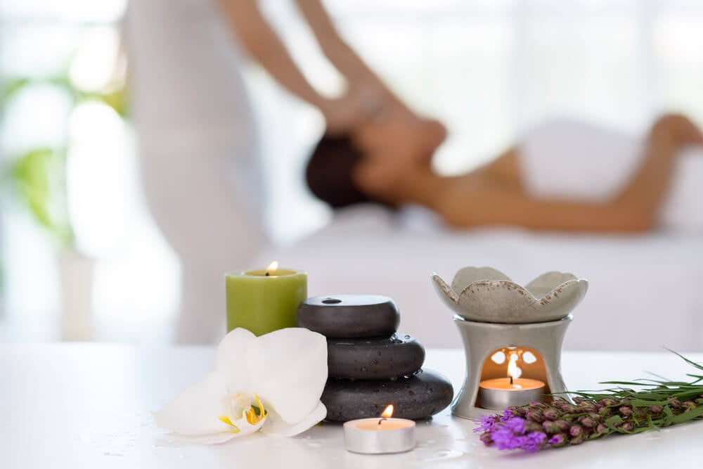 Spa_Spa concept: zen stones, candles and flowers on the background of woman receiving treatment