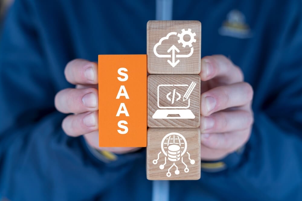 SaaS_Man holding blocks with icons sees abbreviation: SAAS. Concept of Software As A Service ( SAAS ). Networking Technology Web SEO Marketing concept.