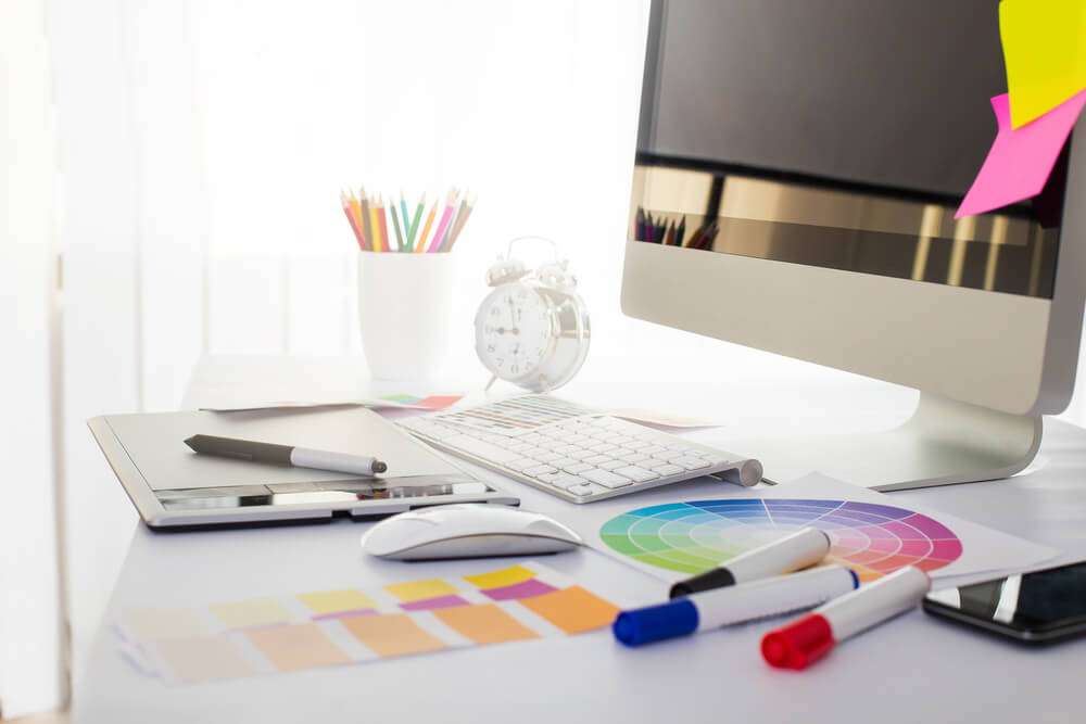 graphic design_Modern office workplace with digital tablet, notepad, colorful pencils, glasses, in morning