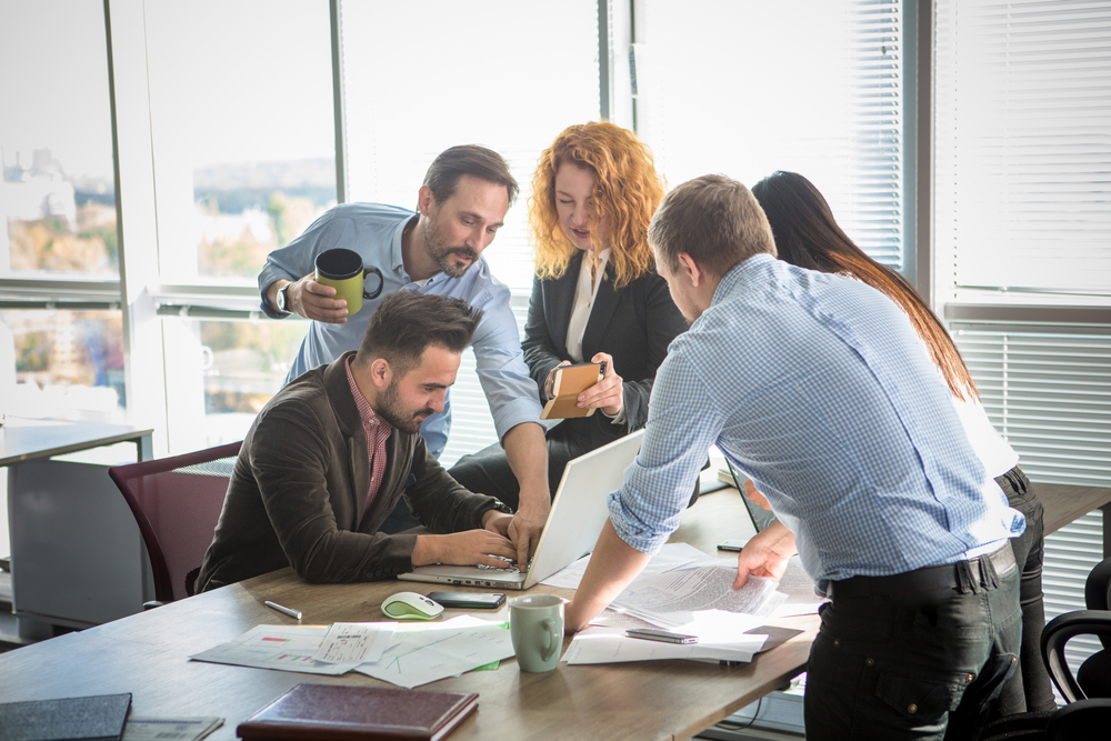 B2B team_Business people showing team work while working in board room in office interior. People helping one of their colleague to finish new business plan. Business concept. Team work.