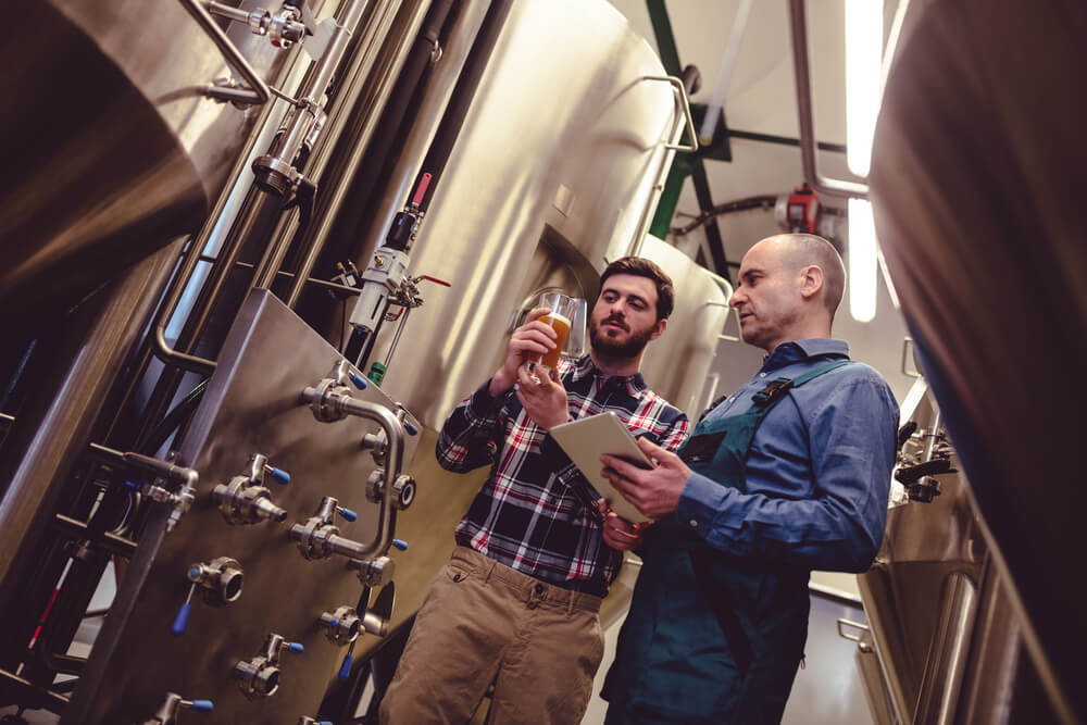 breweries_Low angle view of worker and owner discussing over beer in container at brewery