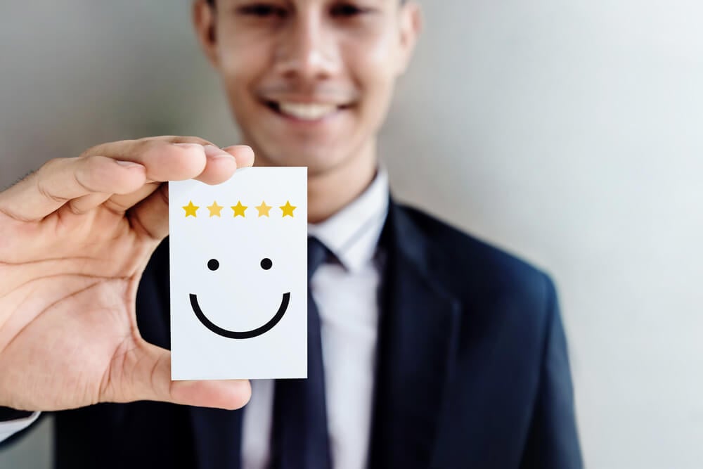 customer loyalty_Customer Experience Concept, Happy Businessman holding Card with Smiley Face and Five Star Rating for his Satisfaction