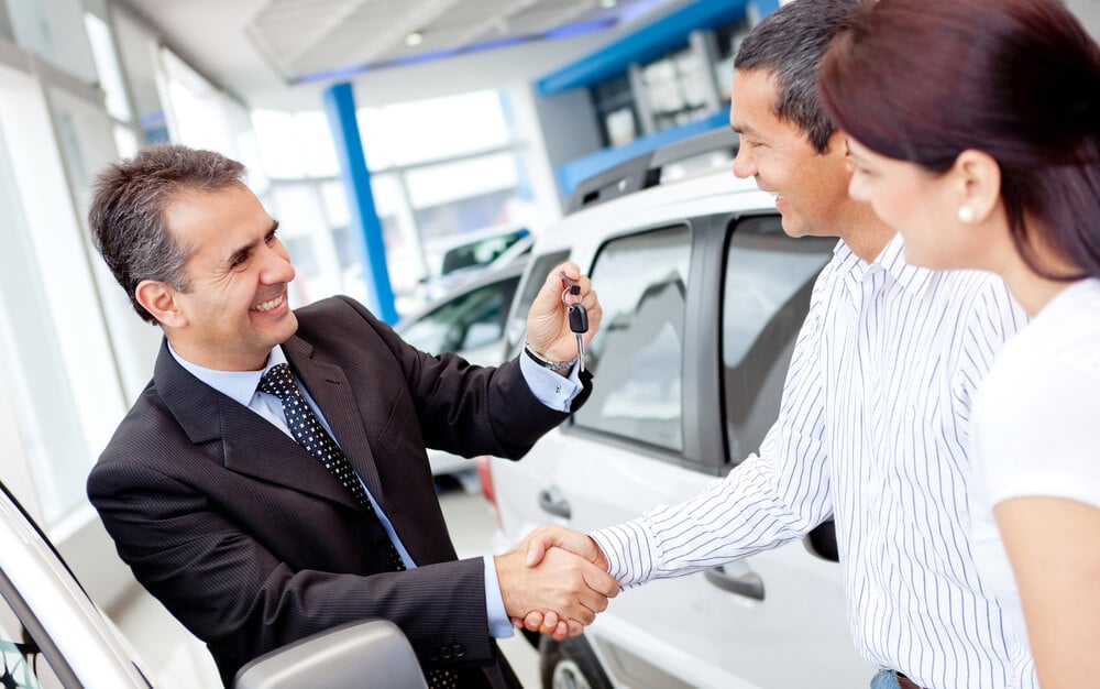 car dealership_Couple buying a car and salesman handling keys