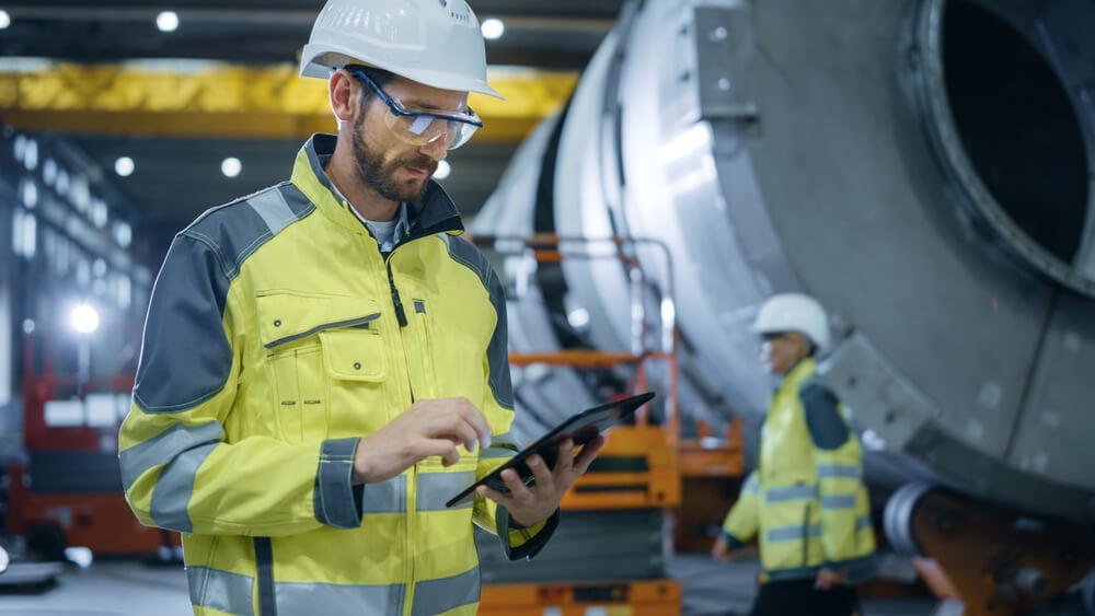 manufacturer_Heavy Industry Engineer Stands in Pipe Manufacturing Factory, Use Digital Tablet Computer. Facility for Construction of Oil, Gas and Fuel Pipeline Transportation Products.