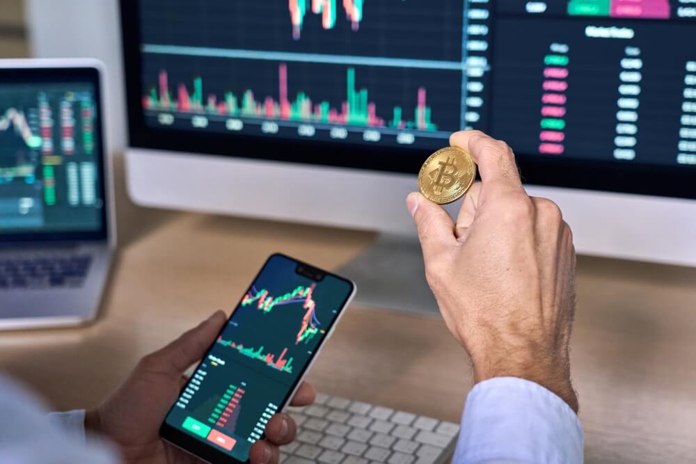crypto market_Business man crypto trader investor analyst holding smartphone and gold bitcoin coin buying cryptocurrency tokens analyzing stock market data investment risks using online trading mobile app