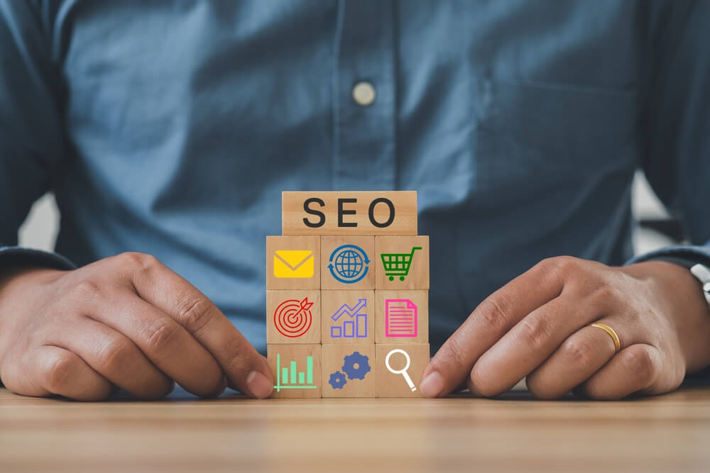 SEO_Hand holds wooden cubes with the icon of magnifying glass with alphabets abbreviation SEO. SEO, Search Engine Optimization ranking concept. Digital marketing strategy of promote traffic to website.