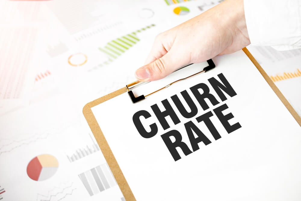 churn rate_Text CHURN RATE on white paper plate in businessman hands with financial diagram. Business concept
