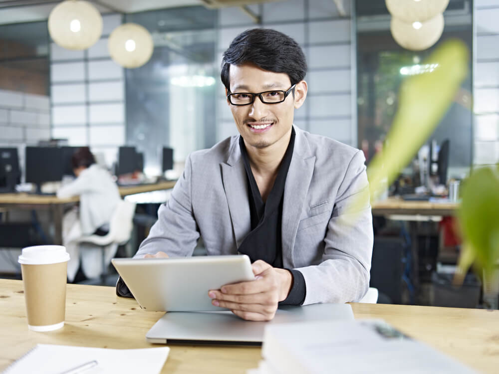 tech firms_young asian business man working in office using tablet computer.