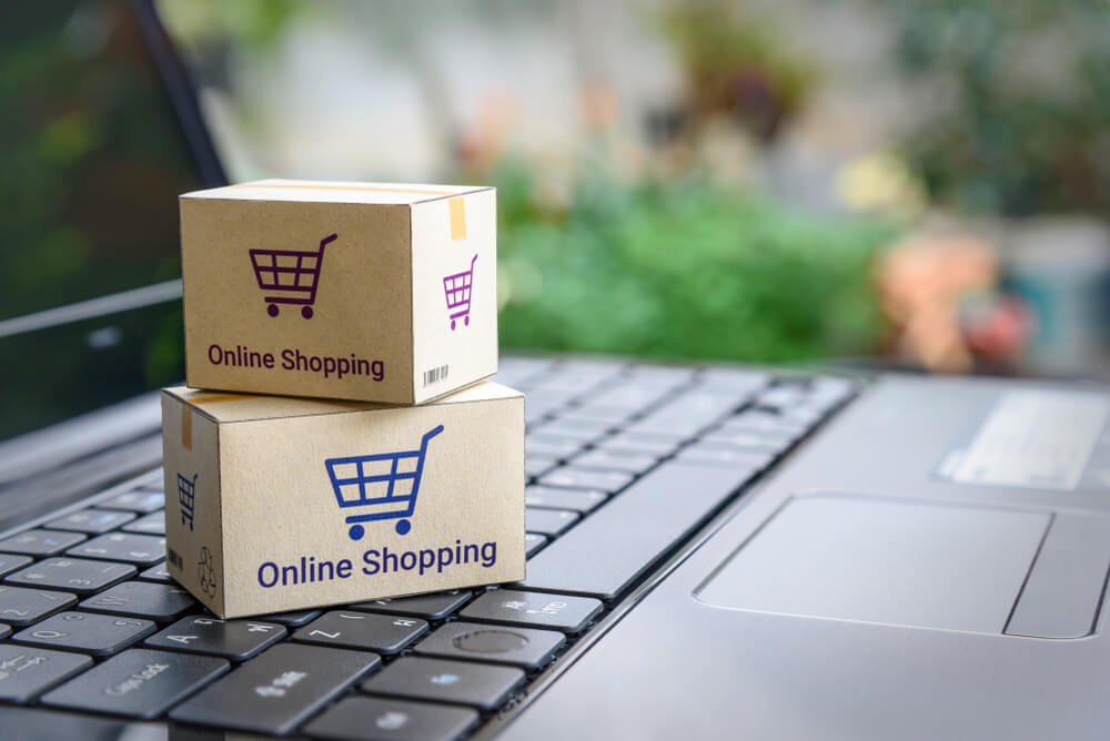 eCommerce_Online shopping / ecommerce and delivery service concept : Paper cartons with a shopping cart or trolley logo on a laptop keyboard, depicts customers order things from retailer sites via the internet.
