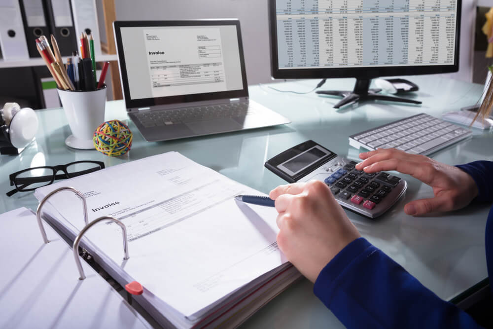 accounting_Close-up Of A Businessperson's Hand Calculating Invoice At Workplace