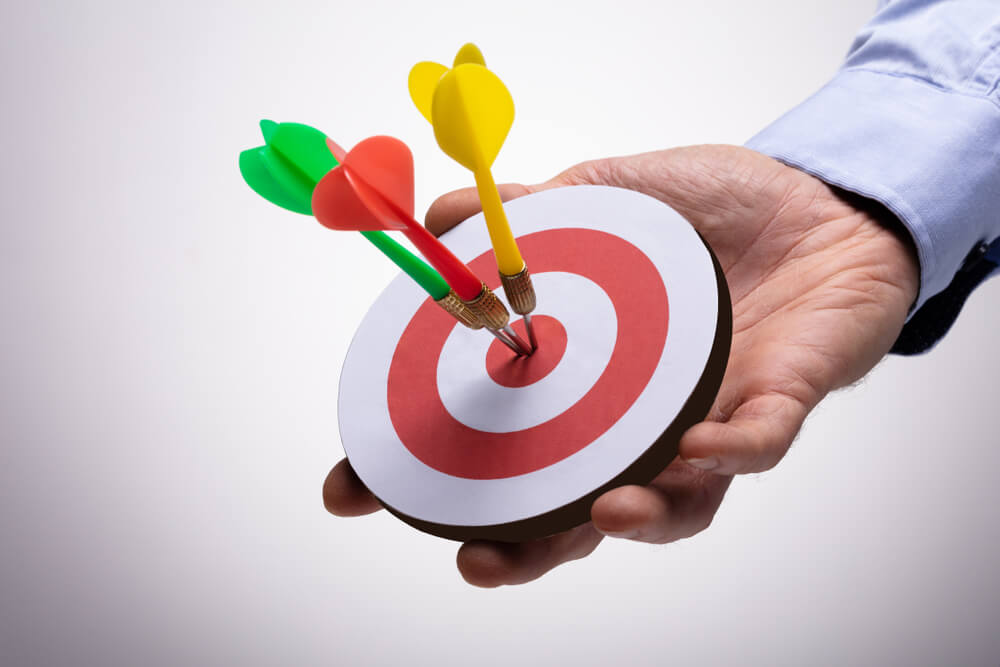 retargeting_Close-up Of Human Hand Holding Colorful Darts On Target Against Background