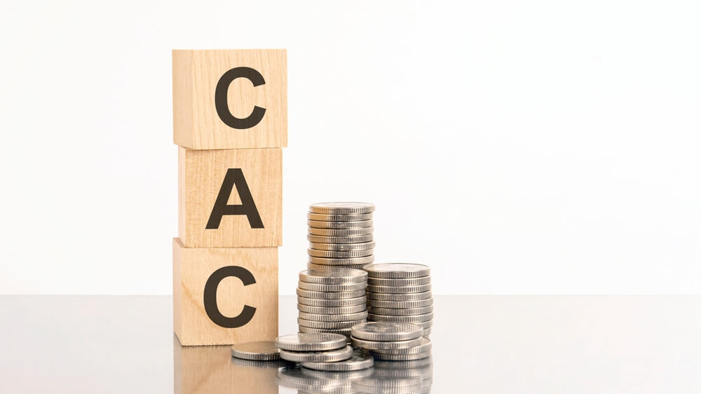 CAC_three wooden cubes with letters CAC, on white table and diagram, business concept. CAC - short for customer acquisition cost