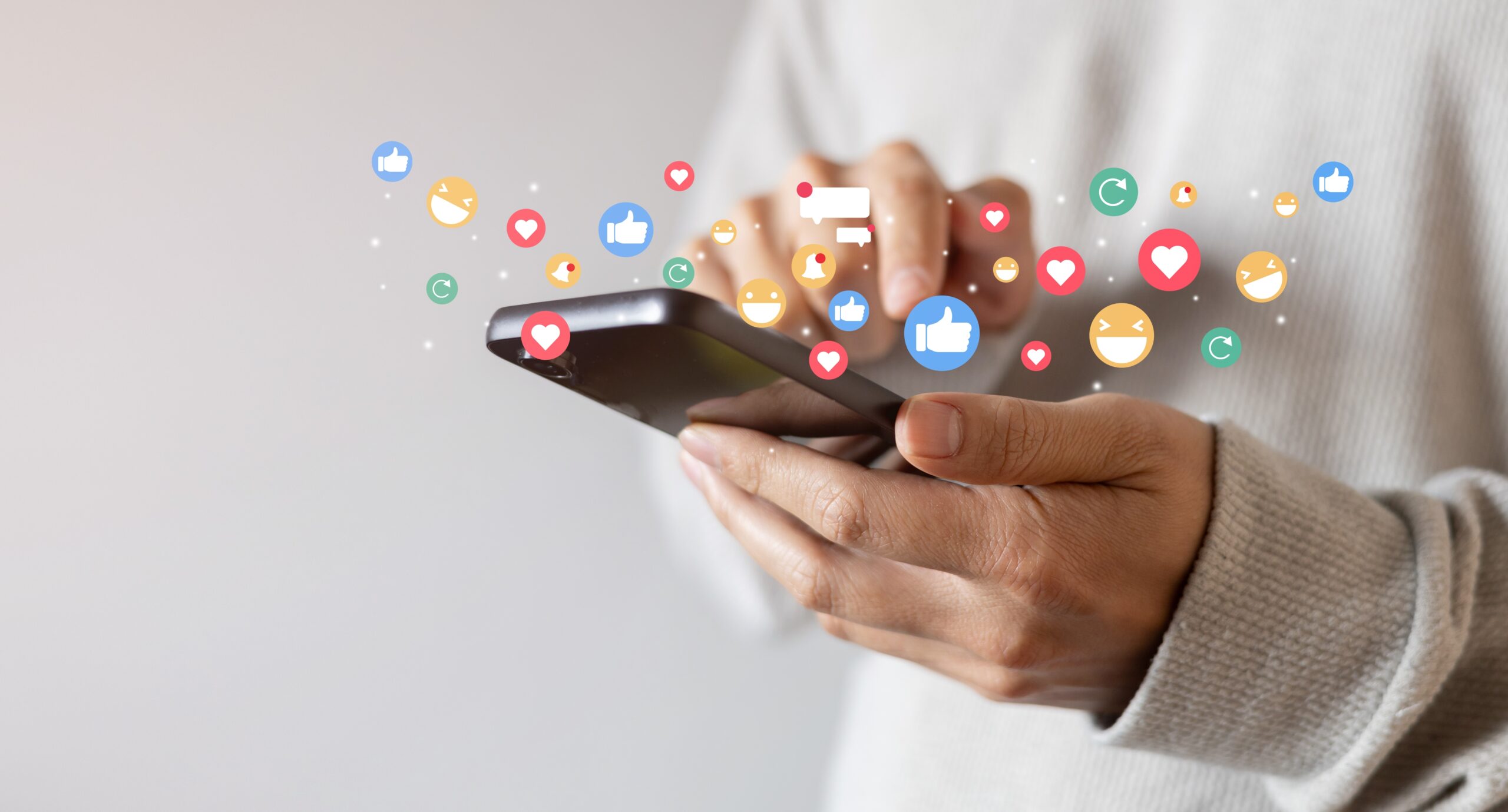 man holds smartphone and social media icons rise above the screen