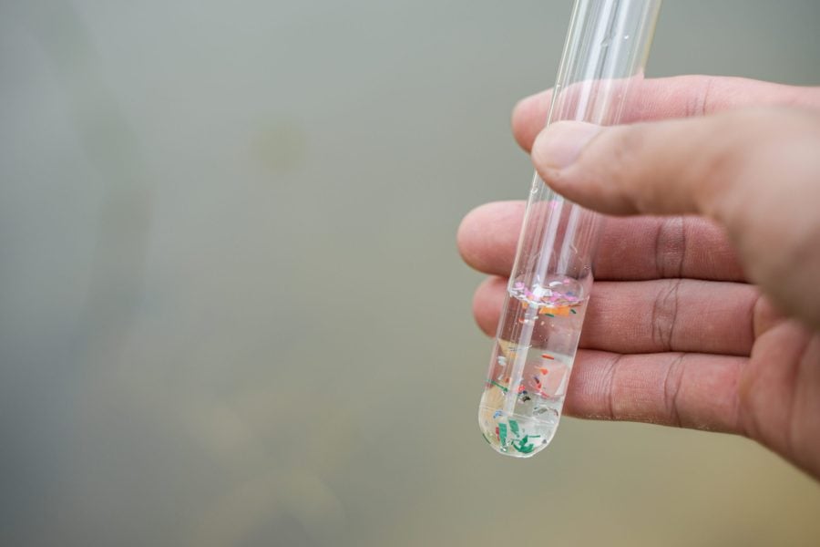 hand holding a tube of microplastics for mass pollution lawsuits